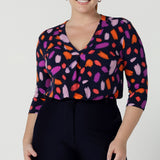 Size 12 woman wears the Jaime top in Palette. A brush stroke inspired abstract print on a navy base with fuchsia, red, orange and pink spots. A v-neck pleat front top great for work to weekend. Comfortable jersey and easy care. Made in Australia for women size 8 - 24. Styled back with navy tailored pants. 