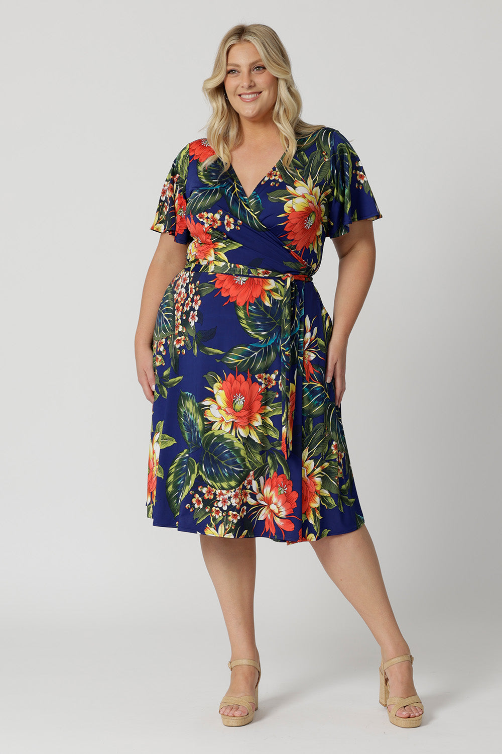 Wrap dress worn by plus sized model has a floral design. The Maggie Knee Length Dress in Bahagia is perfect for cruise holidays and resort style. This floral jersey fabric is easy-care and crease-resistant. Australian made for Australian and New Zealand women. Fashion brand Leina & Fleur stock sizes in sizes 8 to 24. Shop wrap dresses online.