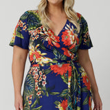 Plus sized model wears maxi dress made with wrap dress detail and flutter sleeve detail. Easy-care and crease-resistant wrap dress is perfect for travel. Leina & Fleur is a woman's clothing brand that have sizes from 8-24. Shop this summer ready dress in petite sizes and plus sizes. Lightweight and packable, fits easily in your luggage for cruise and resort adventures.