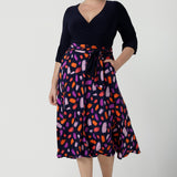 Size 12 woman wears the Nerida dress.  Functioning fit and flare wrap dress with a navy bodice and printed skirt. 3/4 Sleeves and functioning pockets. Made in Australia for women. Size 8 - 24. 