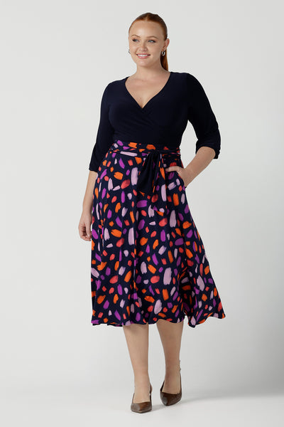 Size 12 woman wears the Nerida dress.  Functioning fit and flare wrap dress with a navy bodice and printed skirt. 3/4 Sleeves and functioning pockets. Made in Australia for women. Size 8 - 24. 