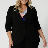 Close up image of a plus sized model wears a black blazer. Introducing our the perfect blend of work wear and off-duty style. Crafted in Australia, this blazer made from easy care scuba crepe fabric. Good workwear blazer for women Australian made. Leina & Fleur brand have available in sizes 8 to 24, shop this comfortable work wear blazer in plus size and petite sizes.