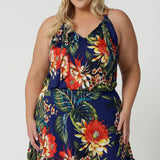 Plus sized woman wears floral midi dress that has halter neck detail and ruffle hem. This easy-care and crease-resistant dress is perfect for travel. Designed in Australia with easy care fabric made of deep blue slinky jersey. Leina & Fleur clothing brand actively stock sizes from 8-24. Shop this summer ready dress in petite sizes and plus sizes.