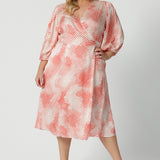 Showing a good dress for plus size women, this silky wrap dress with orange spot print and 3/4 lantern-shaped sleeves is shown on a size 18, curve woman.. Made in Australia by women's clothing brand, Leina & Fleur, wear this 3/4 sleeve wrap dress for wedding guest outfit and summer event  wear. Shop this summer wedding guest and event wear outfit online in sizes 8 to 24.