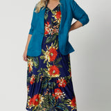 Leina & Fleur's plus sized model wears teal blazer over summer ready floral dress. Linen blazer is in the colour teal. Linen, tencel and cupro were the breathable fabric used to create this breathable blazer. Leina & Fleur stocks sizes from 8-24. Shop this resort ready blazer in petite sizes and plus sizes. 