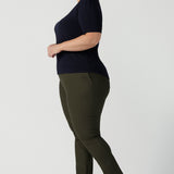 A good top for plus size, curvy women, this short sleeve, boat neck top in navy blue is worn with slim leg, olive green pants by a size 18 woman. A quality top for workwear, this slim fit jersey top is made in Australia by women's clothing brand, Leina & Fleur.