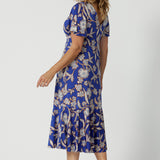 Back view of a good empire line dress for over 40s women With a twist front V neckline, this midi length jersey dress with flutter sleeves also features a ruffle hem. A blue dress with floral print, be holiday ready with this travel and cruise wear dress style. Made in Australia by Australian and New Zealand women's clothes brand, Leina & Fleur, shop their petite to plus sizes dresses online.