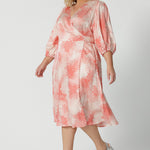 Side view of an event dress for plus size women, this silky wrap dress with orange spot print and 3/4 lantern-shaped sleeves is shown on a size 18, curve woman.. Made in Australia by women's clothing brand, Leina & Fleur, wear this 3/4 sleeve wrap dress for wedding guest outfit and summer event  wear. Shop this summer wedding guest and event wear outfit online in sizes 8 to 24.