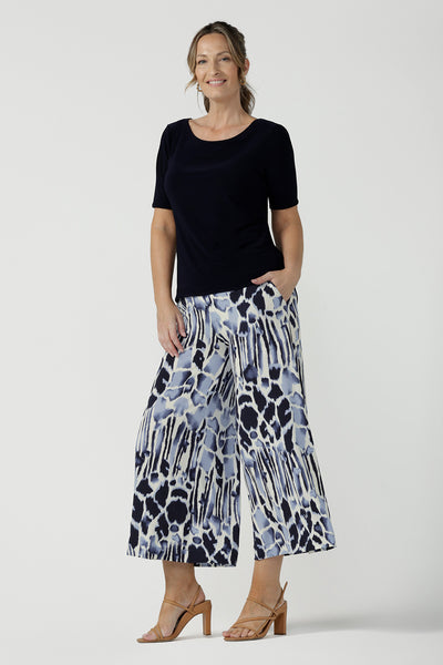 A beautiful and comfortable workwear top for plus size, curvy women, this short sleeve, boat neck top in navy blue is shown on a size 8. Pictured with blue animal printed culottes. A quality top for workwear, this slim fit jersey top is made in Australia by women's clothing brand, Leina & Fleur.