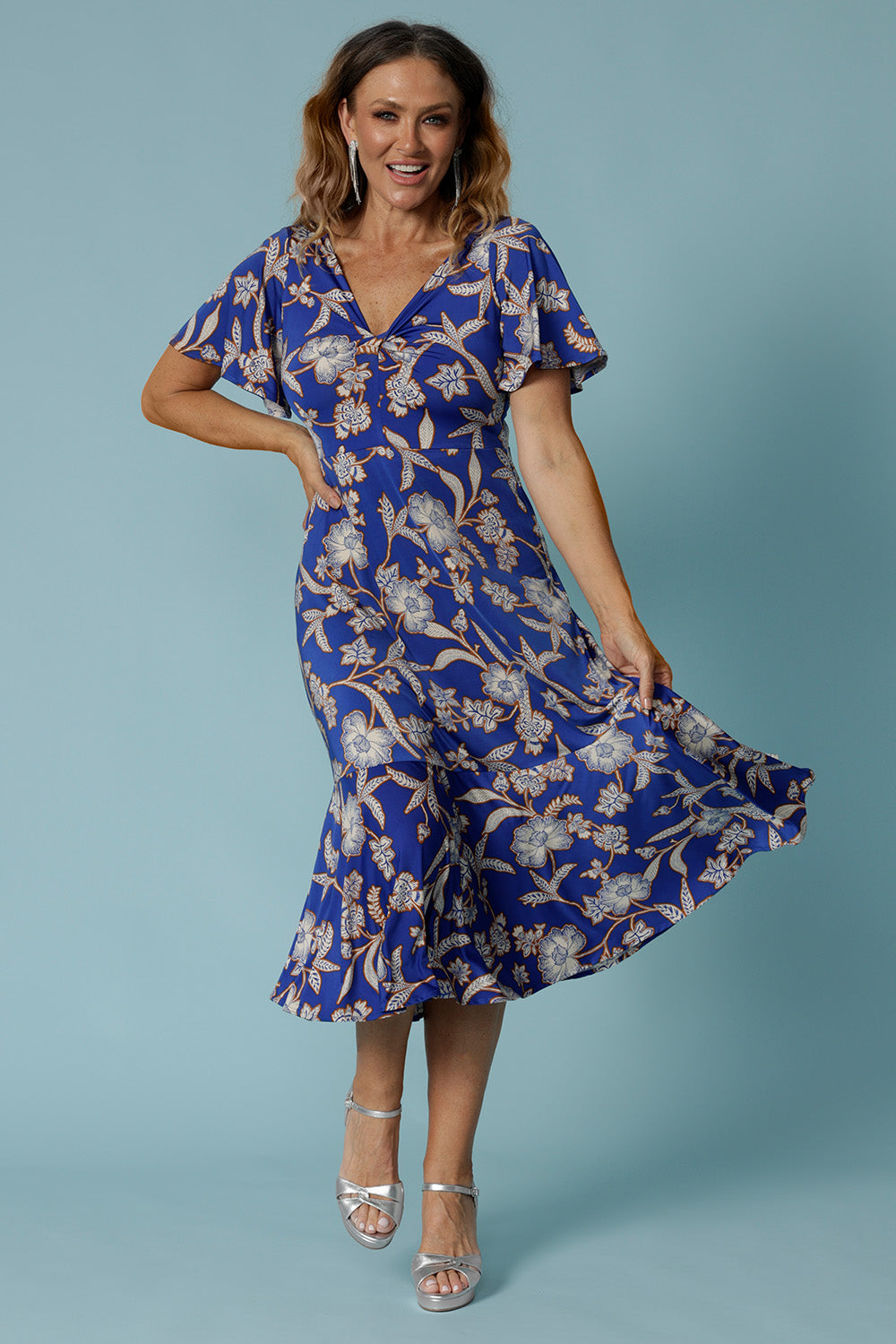 Showing a good empire line dress for over 40s women, this twist front jersey dress in size 12 has flutter sleeves and a ruffle hem. A blue dress with floral print, be holiday ready with this travel and cruise wear dress style. Made in Australia by Australian and New Zealand women's clothes brand, Leina & Fleur, shop their petite to plus sizes dresses online.