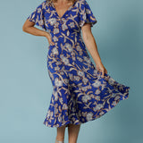 Showing a good empire line dress for over 40s women, this twist front jersey dress in size 12 has flutter sleeves and a ruffle hem. A blue dress with floral print, be holiday ready with this travel and cruise wear dress style. Made in Australia by Australian and New Zealand women's clothes brand, Leina & Fleur, shop their petite to plus sizes dresses online.