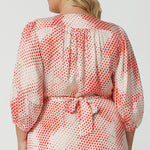 Close up of the back of a silky wrap dress for plus size women. dress for This viscose wrap dress with orange spot print and 3/4 lantern-shaped sleeves is shown on a size 18, curve woman.. Made in Australia by women's clothing brand, Leina & Fleur, wear this 3/4 sleeve wrap dress for wedding guest outfit and summer event  wear. Shop this summer wedding guest and event wear outfit online in sizes 8 to 24.