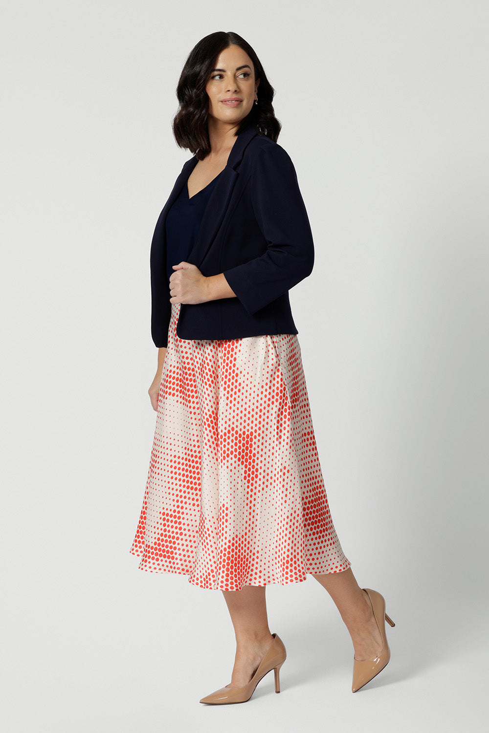 Side view of a good petite wedding guest outfit, a petite,  size 10 woman wears orange-red polka dot print culottes in luxurious Italian viscose fabric with navy cami top and navy jacket. Made in Australia by Australian and New Zealand women's clothing brand, Leina & Fleur, these lightweight culottes are are perfect off-duty summer shorts and pants alternatives. Shop this summer wedding guest and event wear outfit online in sizes 8 to 24.