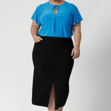 Australian made black workwear skirt seen on over 40's woman paired with opal coloured shirt and black heels for an elevated workwear look. Sizes 8-24 available at Leina & Fleur.