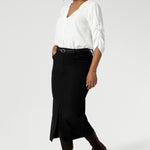 Image of Australian made black workwear skirt seen on over 30's woman paired with white blouse and brown boots for an elevated workwear look. Sizes 8-24 available at Leina & Fleur.
