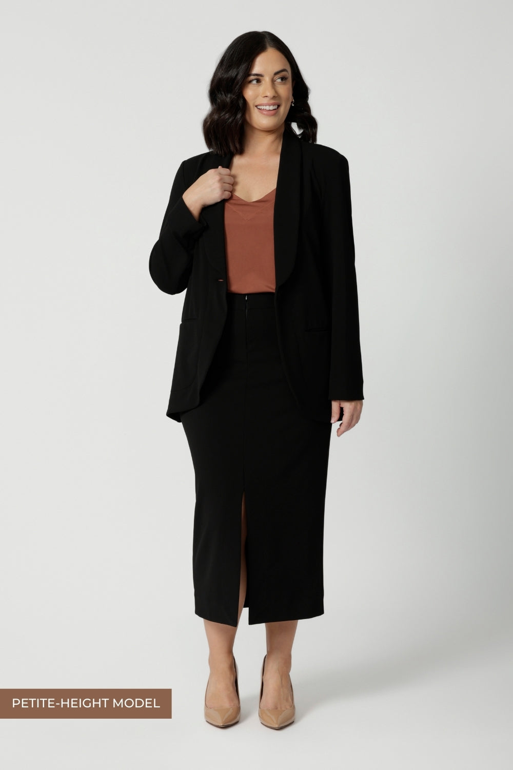 Petite height model wears straight-cut black midi skirt in lightweight scuba crepe jersey, designed by Australian and New Zealand women's clothing brand, Leina & Fleur. This stretchy, easy-care skirt is a perfect skirt for petite women, an ideal as both a workwear skirt and off duty skirt.