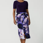A size 10 woman wears the Aaron Midi Skirt in Jacaranda. A printed Midi length skirt in purple florals. Made in Australia for women size 8-24. 