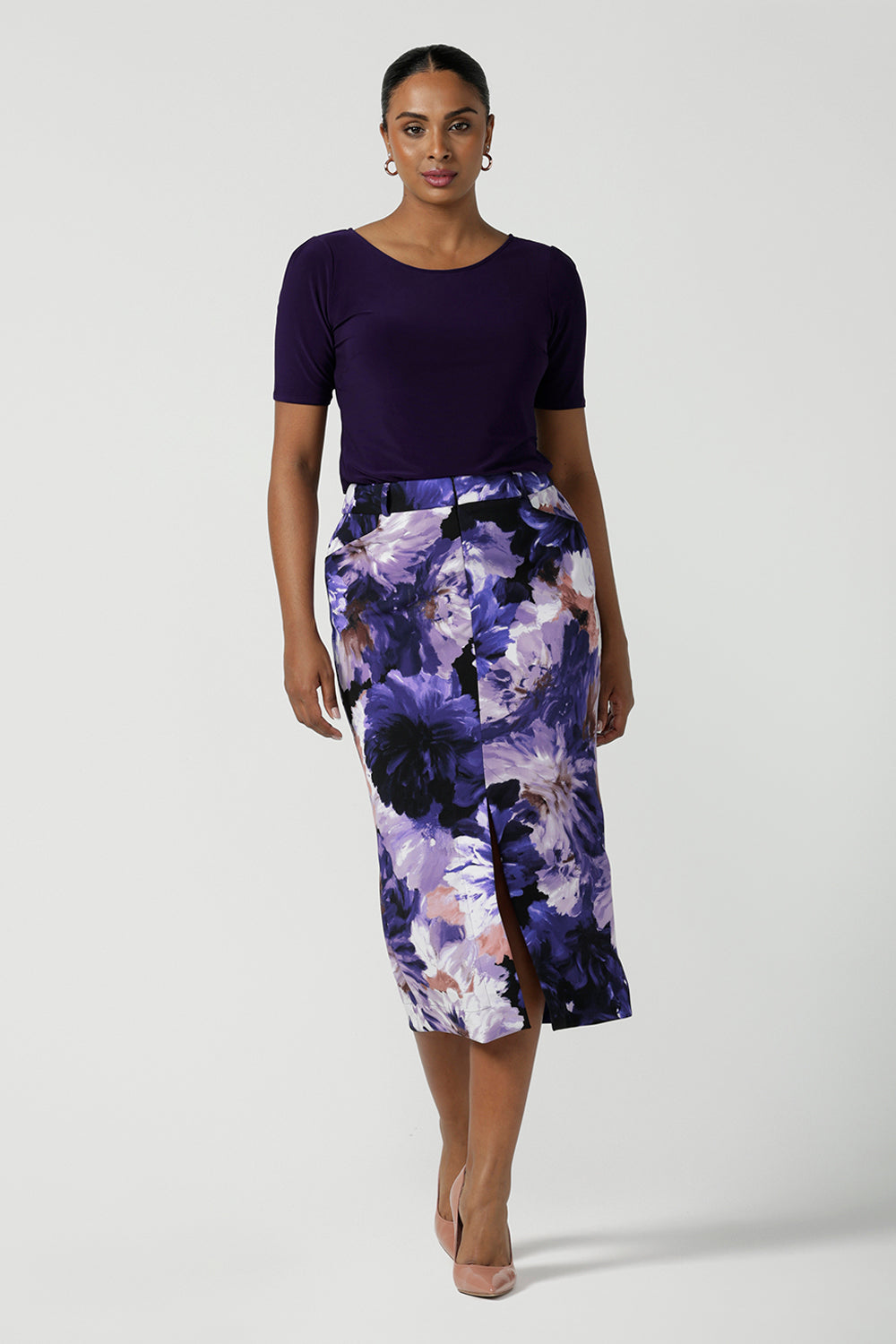 A size 10 woman wears the Aaron Midi Skirt in Jacaranda. A printed Midi length skirt in purple florals. Made in Australia for women size 8-24. 