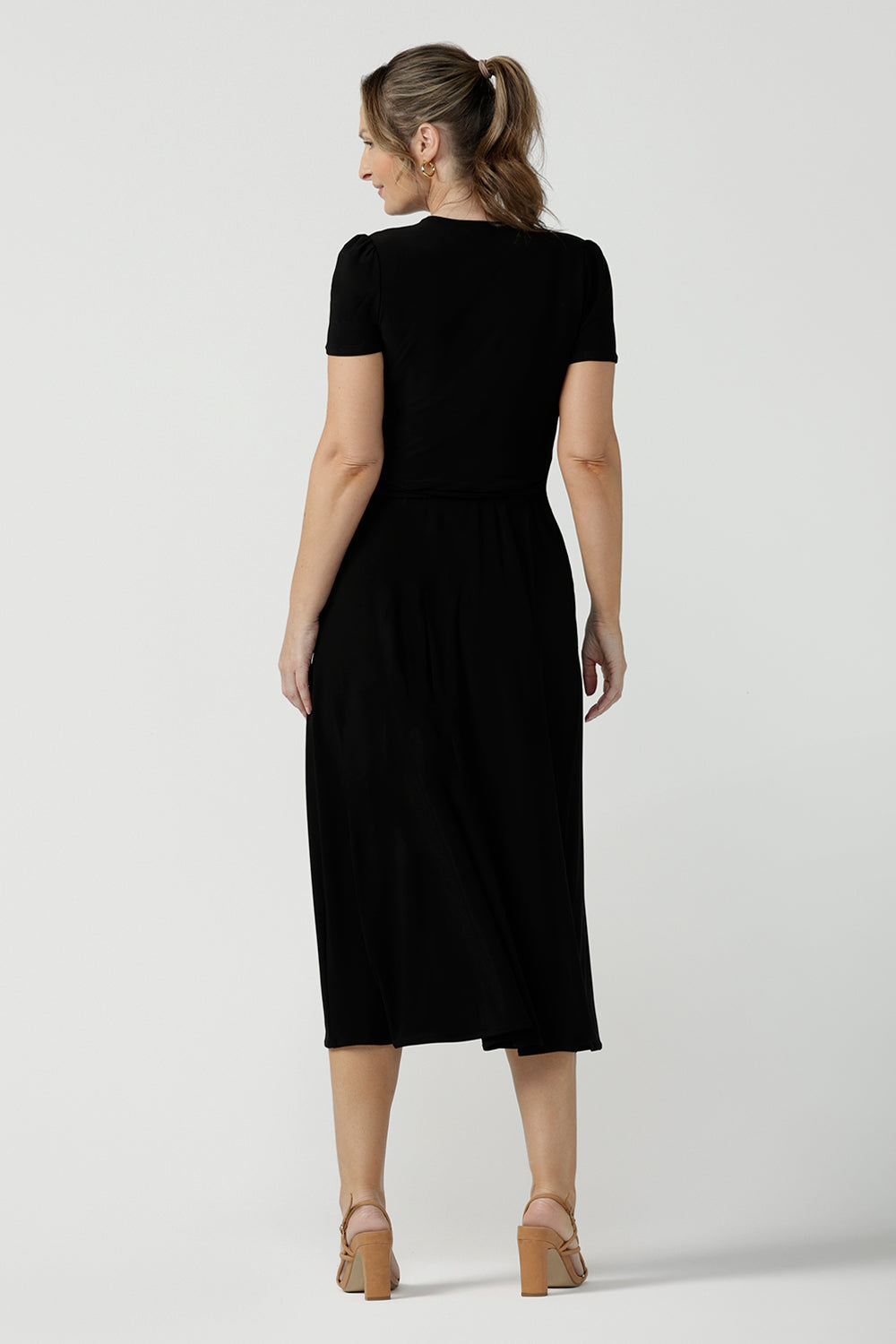 Back view of size inclusive jersey wrap dress in size 8. Curvy women workwear midi dress with pockets. Black dress. 