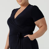 Close up of a curvy, size 18 woman wearing a navy, wrap dress with short sleeves. A great dress for summer casual wear, or for travel. Shop made in Australia dresses in petite to plus sizes online at Australian fashion brand, Leina & Fleur.