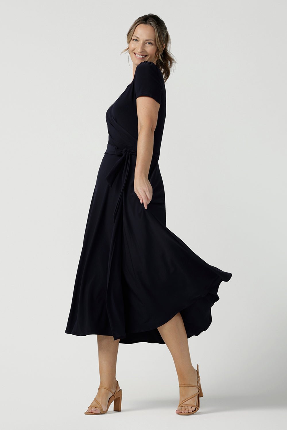 An over 40, size 10 woman wearing a navy, wrap dress with short sleeves. A great dress for summer casual wear, or for travel. Shop made in Australia dresses in petite to plus sizes online at Australian fashion brand, Leina & Fleur.