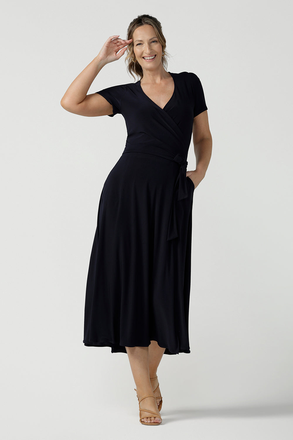 An over 40, size 10 woman wearing a navy, wrap dress with short sleeves. A great dress for summer casual wear, or for travel. Shop made in Australia dresses in petite to plus sizes online at Australian fashion brand, Leina & Fleur.