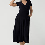 An over 40, size 10 woman wearing a navy, wrap dress with short sleeves. A great dress for summer casual wear, or for travel. Shop made in Australia dresses in petite to plus sizes online at Australian fashion brand, Leina & Fleur.