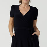 Close up of an over 40, size 10 wearing a navy, wrap dress with short sleeves. A great dress for summer casual wear, or for travel. Shop made in Australia dresses in petite to plus sizes online at Australian fashion brand, Leina & Fleur.