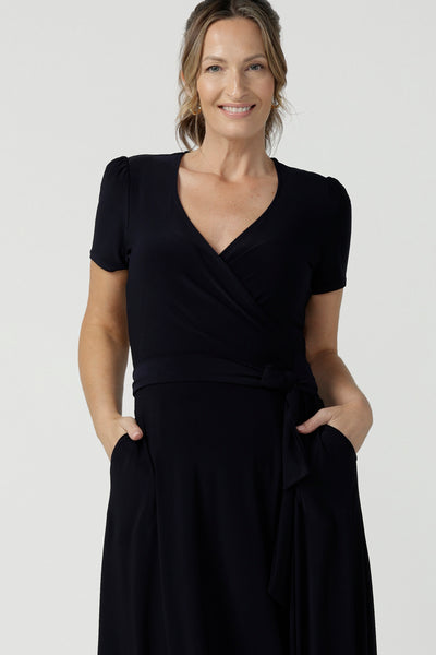 Close up of an over 40, size 10 wearing a navy, wrap dress with short sleeves. A great dress for summer casual wear, or for travel. Shop made in Australia dresses in petite to plus sizes online at Australian fashion brand, Leina & Fleur.