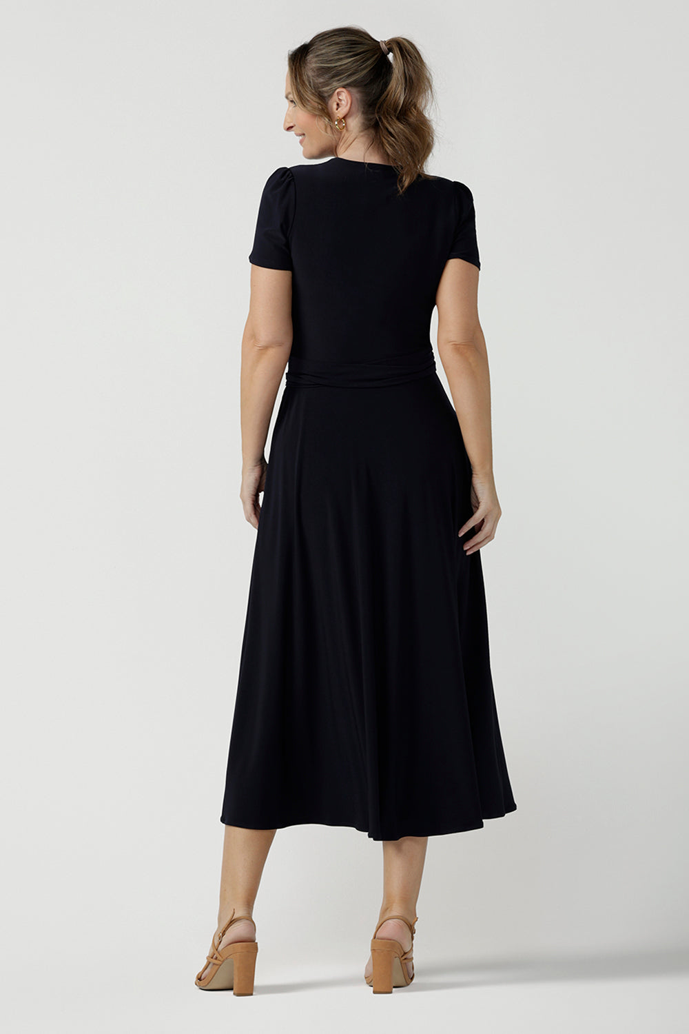 Back view of an over 40, size 10 woman wearing a navy, wrap dress with short sleeves. A great dress for summer casual wear, or for travel. Shop made in Australia dresses in petite to plus sizes online at Australian fashion brand, Leina & Fleur.