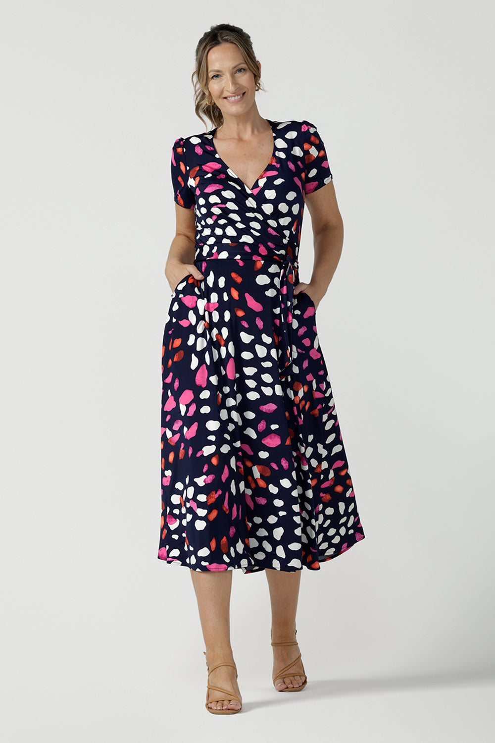 An over 40, size 10 woman wearing a abstract jersey print, wrap dress with short sleeves. A great dress for summer casual wear, or for travel. Shop made in Australia dresses in petite to plus sizes online at Australian fashion brand, Leina & Fleur.