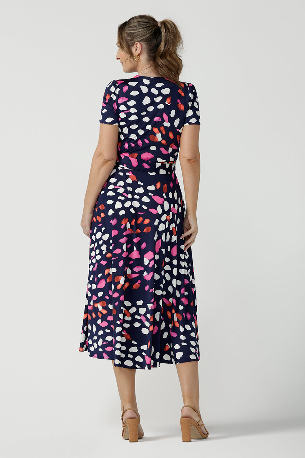 Back view of an over 40, size 10 woman wearing a abstract jersey print, wrap dress with short sleeves. A great dress for summer casual wear, or for travel. Shop made in Australia dresses in petite to plus sizes online at Australian fashion brand, Leina & Fleur.
