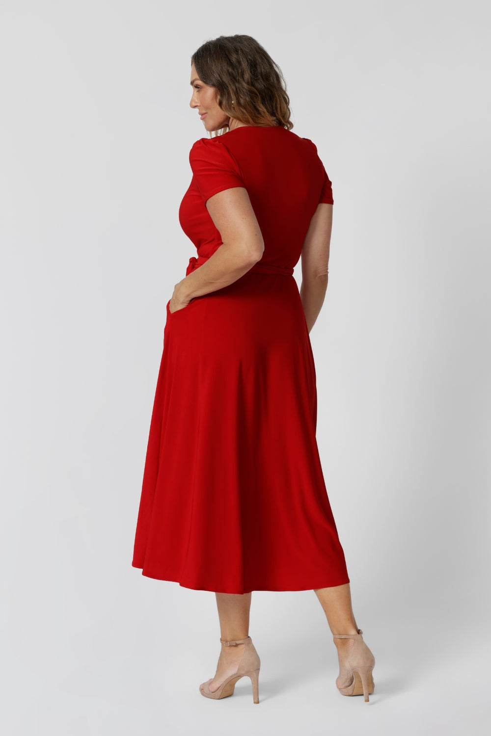 Back view of 40 year old woman wearing a red wrap dress made from soft dry touch jersey fabric. This party ready dress is both comfortable and stylish. Midi length perfect for any occasion, especially during the warm festive season. Fashion label Leina & Fleur stocks this dress in sizes 8-24.