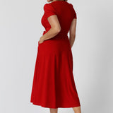 Back view of 40 year old woman wearing a red wrap dress made from soft dry touch jersey fabric. This party ready dress is both comfortable and stylish. Midi length perfect for any occasion, especially during the warm festive season. Fashion label Leina & Fleur stocks this dress in sizes 8-24.