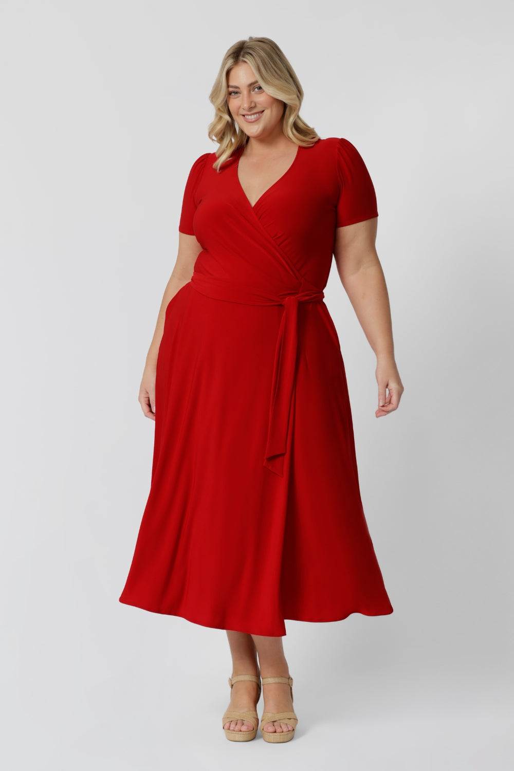 Plus sized woman wears midi length red dress with functioning tie in the front. This stunning wrap dress is crafted from a soft, dry touch jersey fabric, making it both comfortable and stylish. With its elegant midi length, it’s perfect for any occasion. Designed and made in Australia, this versatile dress is available in sizes 8 to 24, ensuring a flattering fit for everyone. Whether you're attending a holiday party or a casual gathering. 