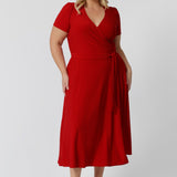 Plus sized woman wears midi length dress perfect for any occasion. Get festive season ready with this red wrap dress. Made in Australia, this party ready dress is available in sizes 8 - 24, ensuring a flattering fit for everyone. Leina & Fleur Fashion brand proudly stocks petite and plus sized friendly clothing.