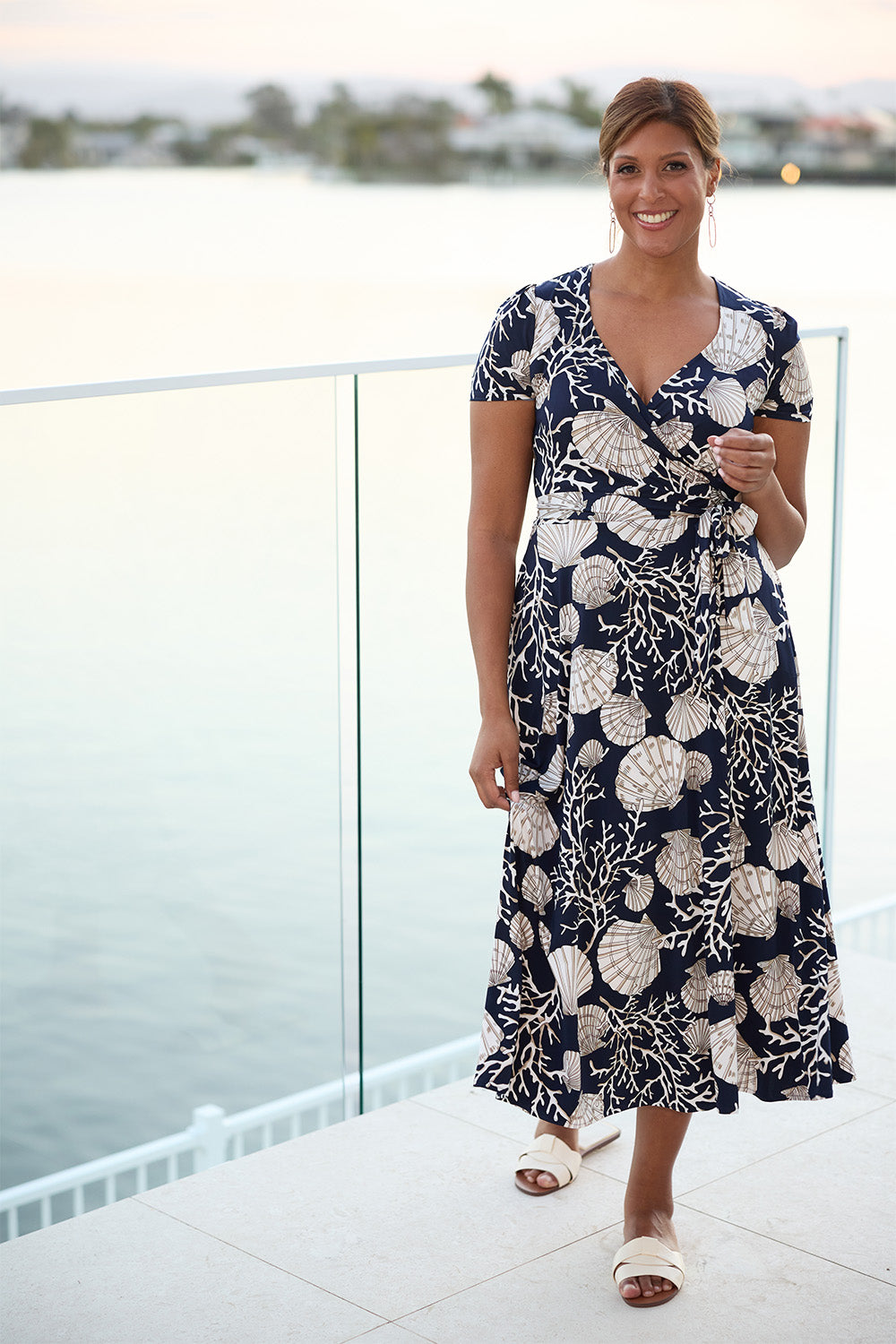 Silky and fluid on the body, it features a functioning wrap front with extended waist ties and a flattering A-line skirt. The Seashells print pairs a refined marine motif with a deep navy base. Made in Australia.
