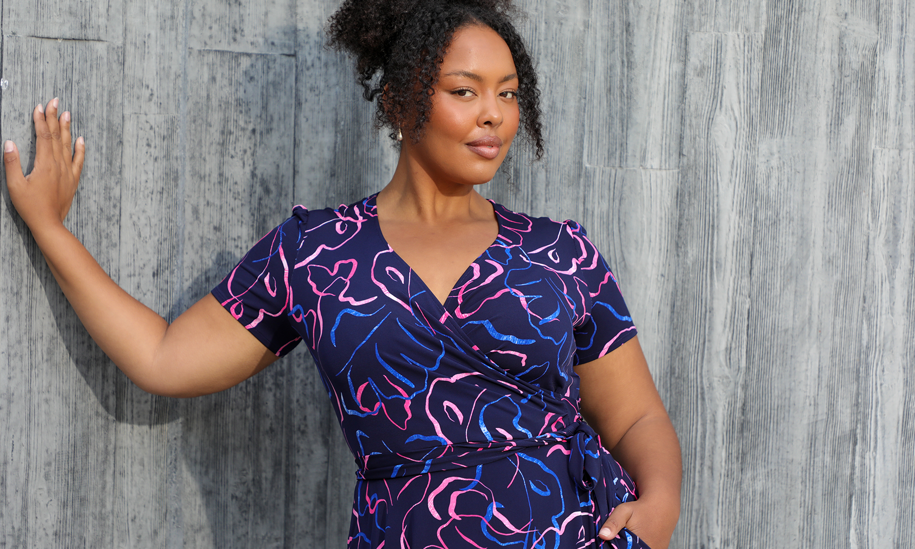 A size 18 woman wears a short sleeve plus size wrap dress by Australian fashion brand, Leina & Fleur. Shop their made in Australia wrap dresses for work online in sizes 8 to 24. 