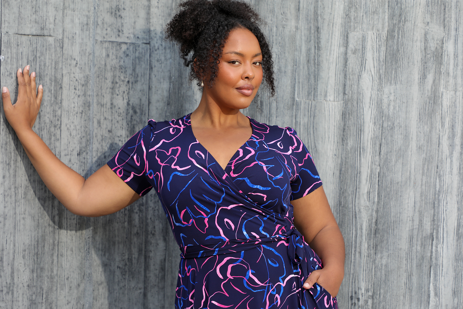 A size 18 woman wears a short sleeve plus size wrap dress by Australian fashion brand, Leina & Fleur. Shop their made in Australia wrap dresses for work online in sizes 8 to 24. 