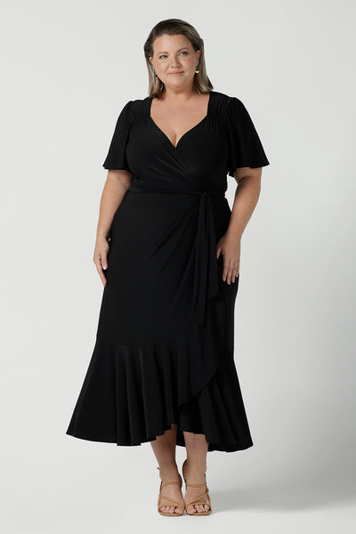 Size 18 woman wears a Alita dress in black. An elegant wrap dress with a tier and sweetheart neckline and flutter sleeve. Made in Australia for women size 8 - 24.