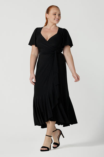 Size 12 woman wears a Alita dress in black. An elegant wrap dress with a tier and sweetheart neckline and flutter sleeve. Made in Australia for women size 8 - 24.