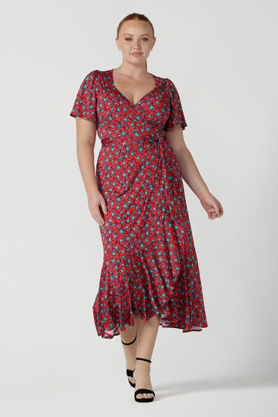 Size 12 curvy woman wearing a size 12 wrap dress in soft slinky jersey. The beautiful Rio print has seventies inspired florals with aqua.Romantic valentines day dressing, frill hem and flutter sleeve for curvy women size 8 - 24.