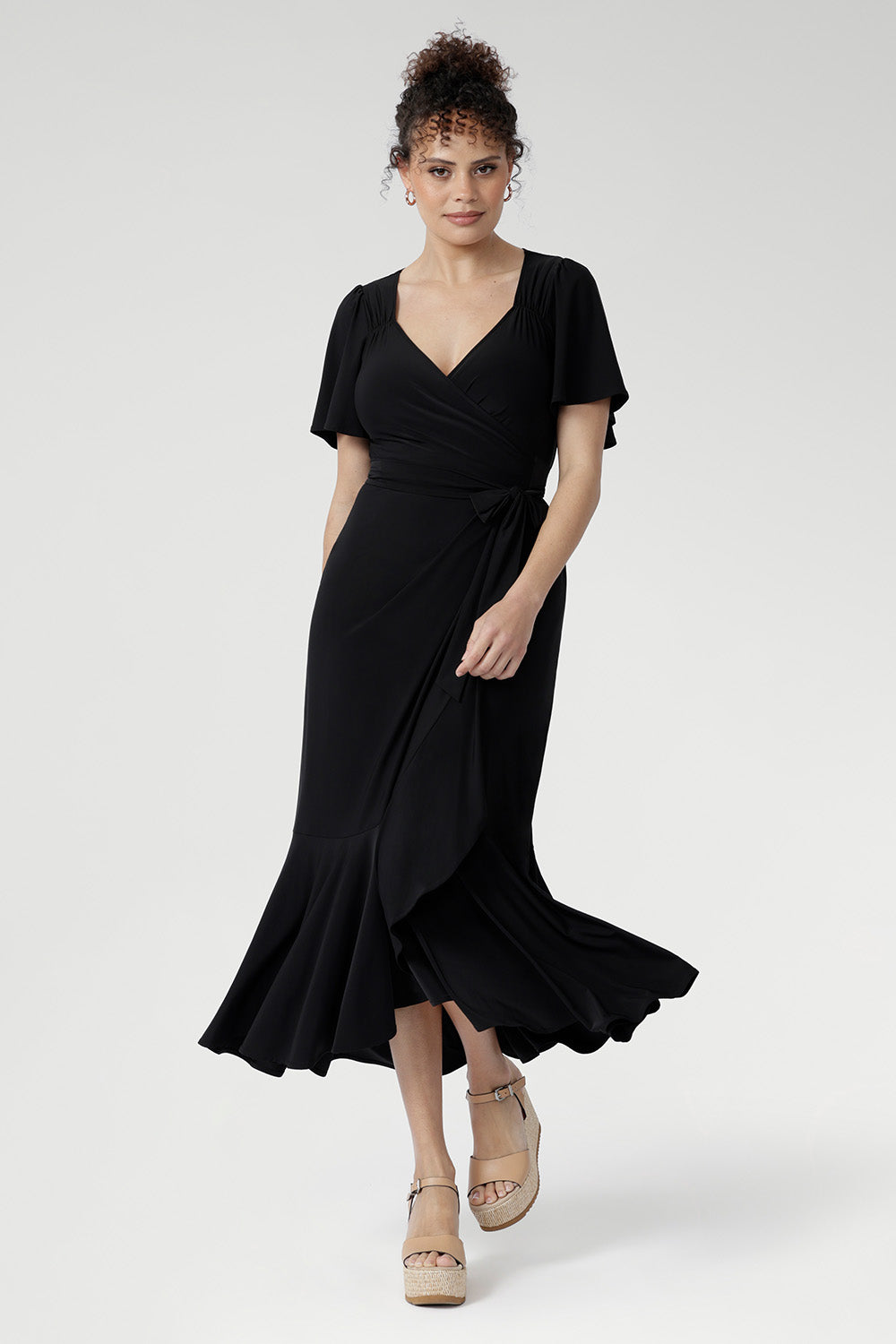 Women’s black wrap dress featuring sweetheart neckline, waist ruching, and flutter sleeves, Alita Dress for luxe evening style.
