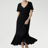 Women’s black wrap dress featuring sweetheart neckline, waist ruching, and flutter sleeves, Alita Dress for luxe evening style.