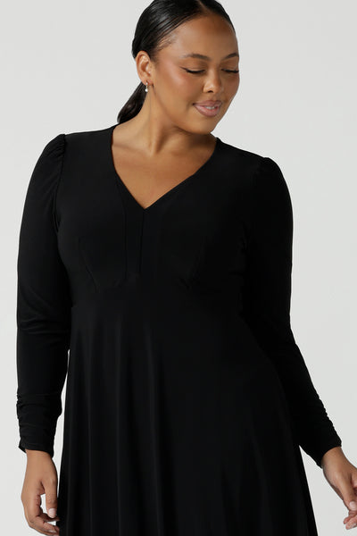 Close up of a view of a size 16 woman wears a Alyssa Dress in jersey. V-neckline style great for work to weekend wear. Corporate dress for women. Travel friendly with an empire line style. Midi dress and styled back with black strappy heels. Made in Australia for women size 8 - 24.