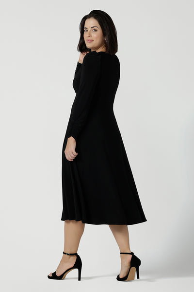 Back view of size 10 Alyssa Dress in jersey. V-neckline style great for work to weekend wear. Corporate dress for women. Travel friendly with an empire line style. Midi dress and styled back with black strappy heels. Made in Australia for women size 8 - 24.