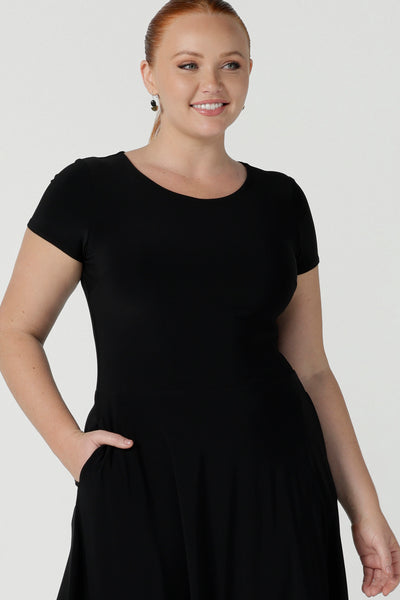 Close up of a dress in black is a slim fit round neck dress with waist seam and tier at the bottom. Functioning pockets. Great for work or event occasions. Made in Australia. Size inclusive fashion for women size 8 - 24.