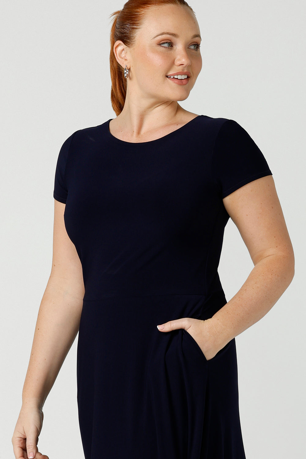 If you're looking for dresses made in Australia, look to this elegant navy dress. Showing a close up of the high neck, pockets and short sleeves of a navy blue  dress with flared skirt and ruffle hemline, this is a good workwear dress as well as a classic cocktail dress. With a midi-length skirt, shop this dress in plus sizes as well as petite thanks to made-in-Australia women's clothing brand, Lena & Fleur.