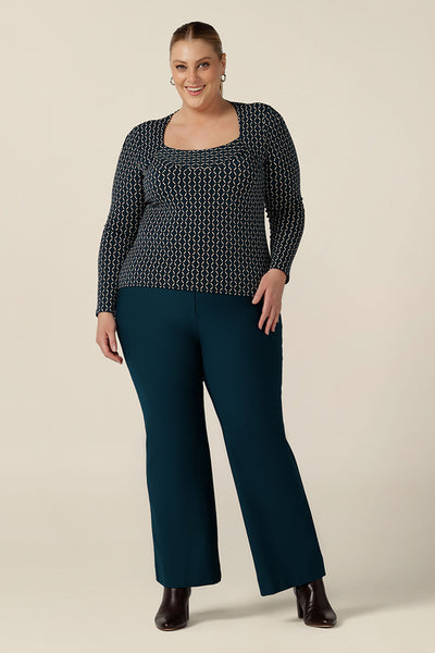 A plus size, size 18 woman wears petrol blue, tailored bootcut pants with a long sleeve printed top for work wear. Made in Australia in ponte fabric, these comfortable work pants are great for curvy women - shop in sizes 8 to 24. 