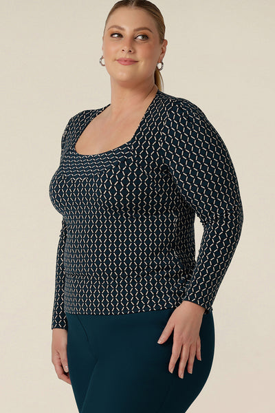 A fuller figure, size 18 woman wears a long sleeve top with squared scoop neckline. In geometric print jersey, this comfortable top is good for work wear capsule wardrobes. Made in Australia, shop tops in sizes 8 to 24, petite to plus sizes.
